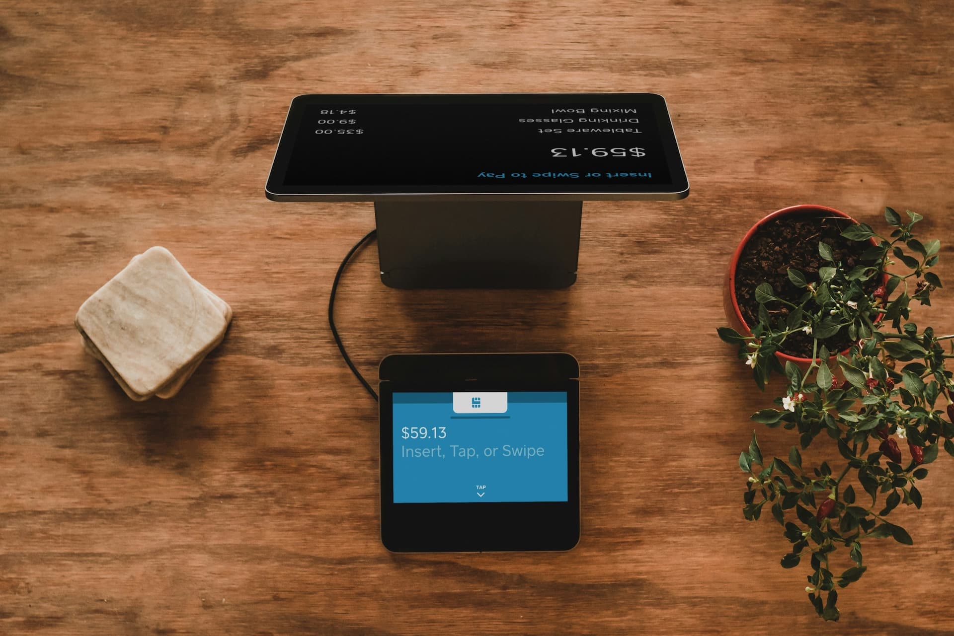 POS tablet on wooden counter with plant