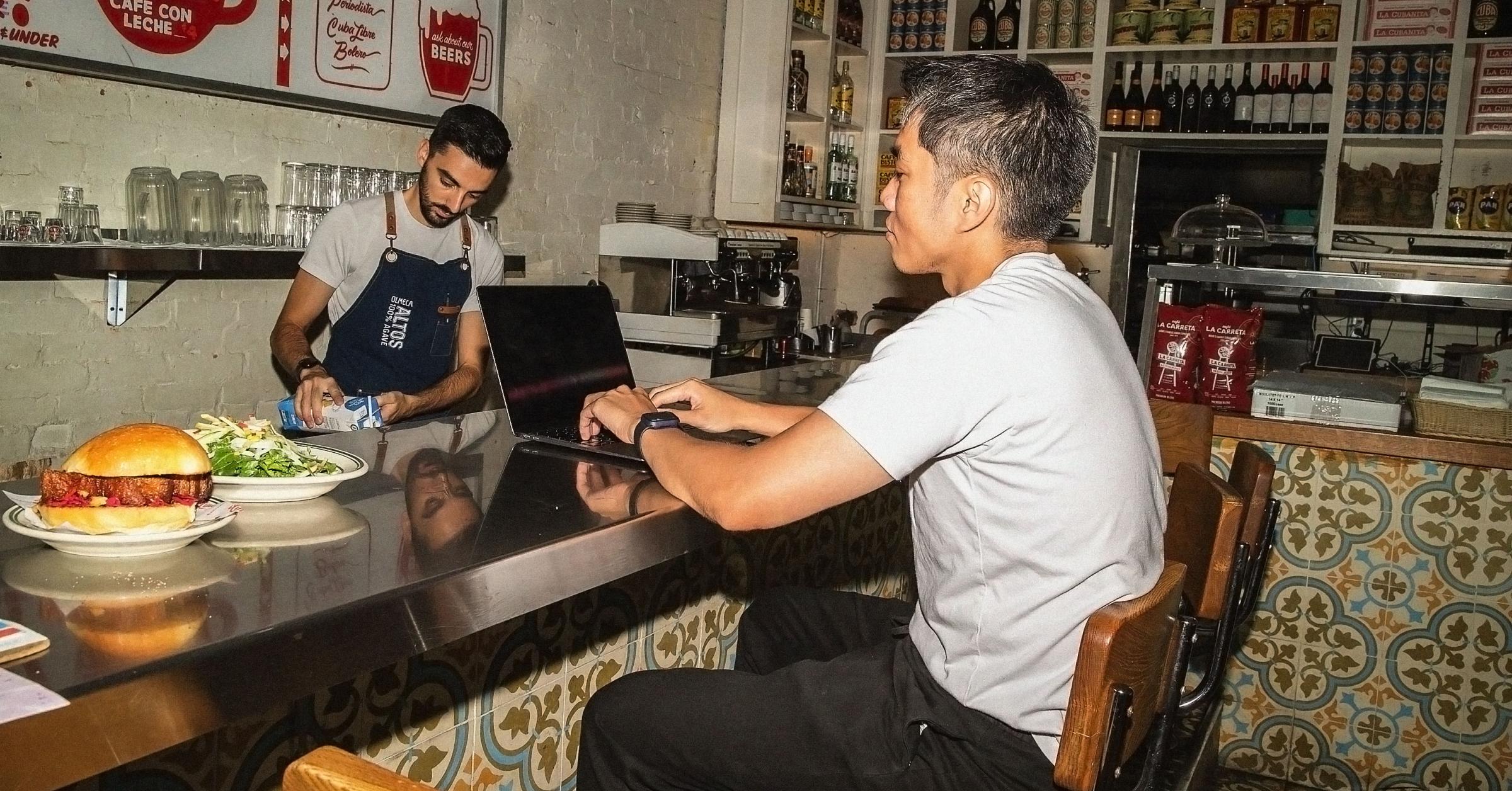 Restaurant owner on laptop at restaurant bar top