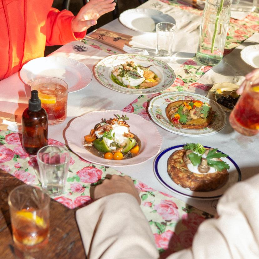 A table covered in a floral tablecloth, with plates full of food on top of it