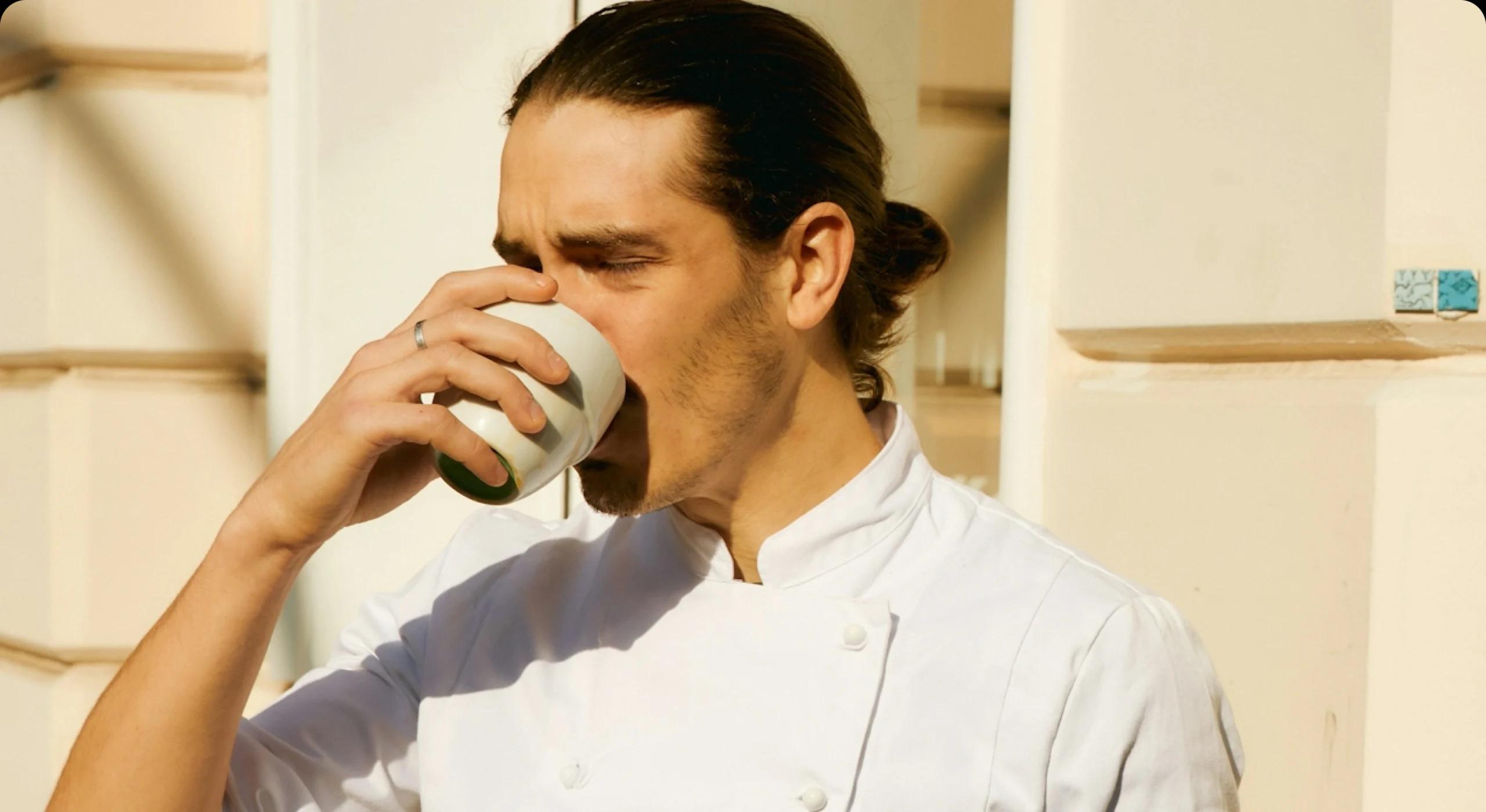 Chef taking a sip of coffee outside in sunshine