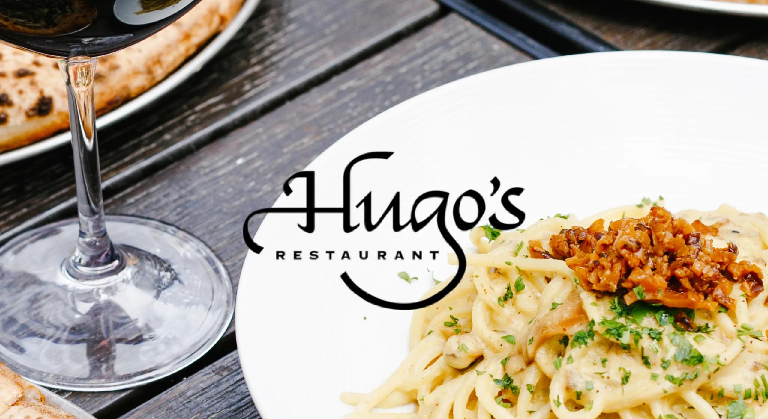 Image of plate of spaghetti on table with wine, Hugo's logo on top