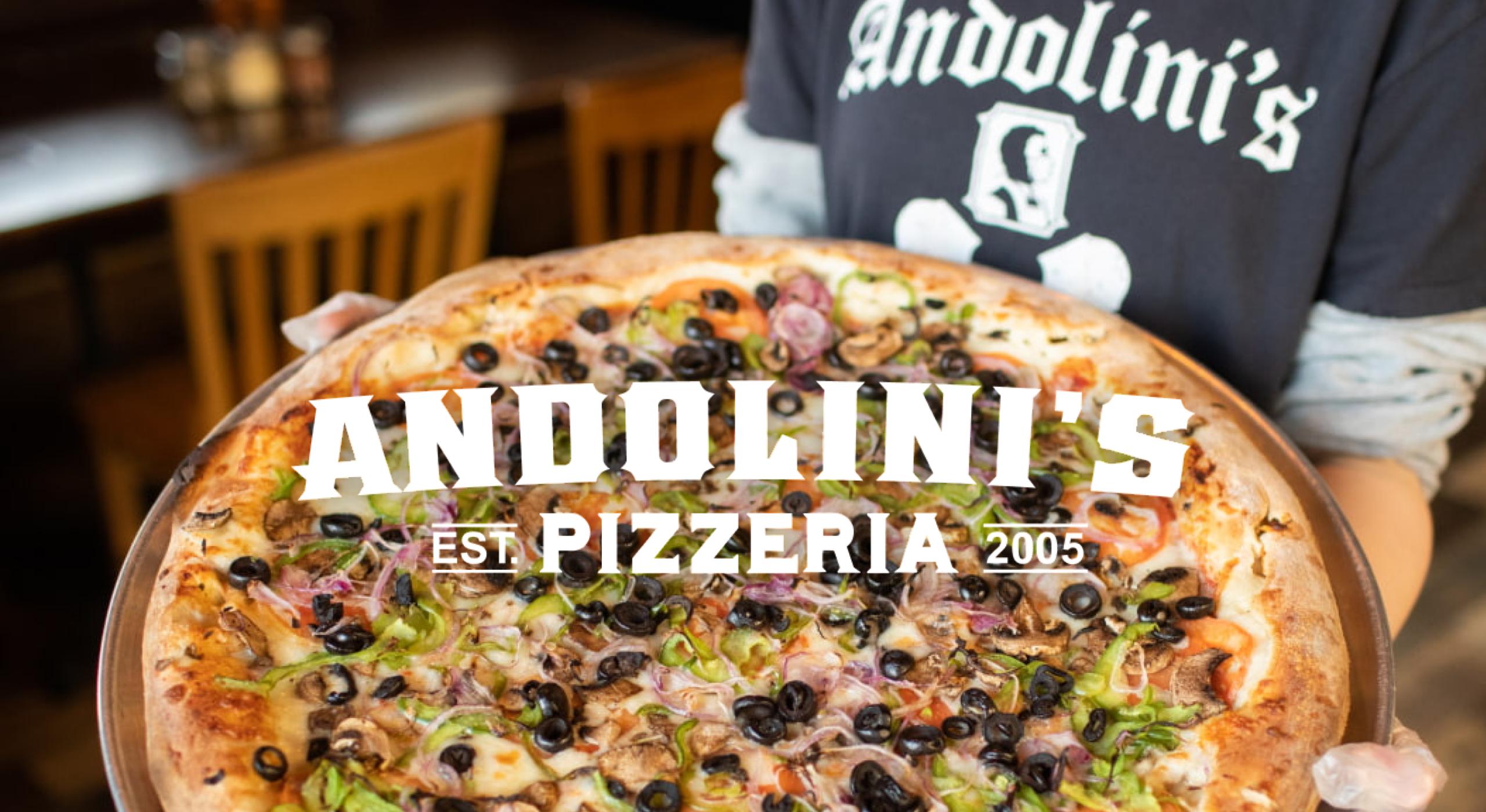 Man holding large pizza at Andolini's Pizzeria