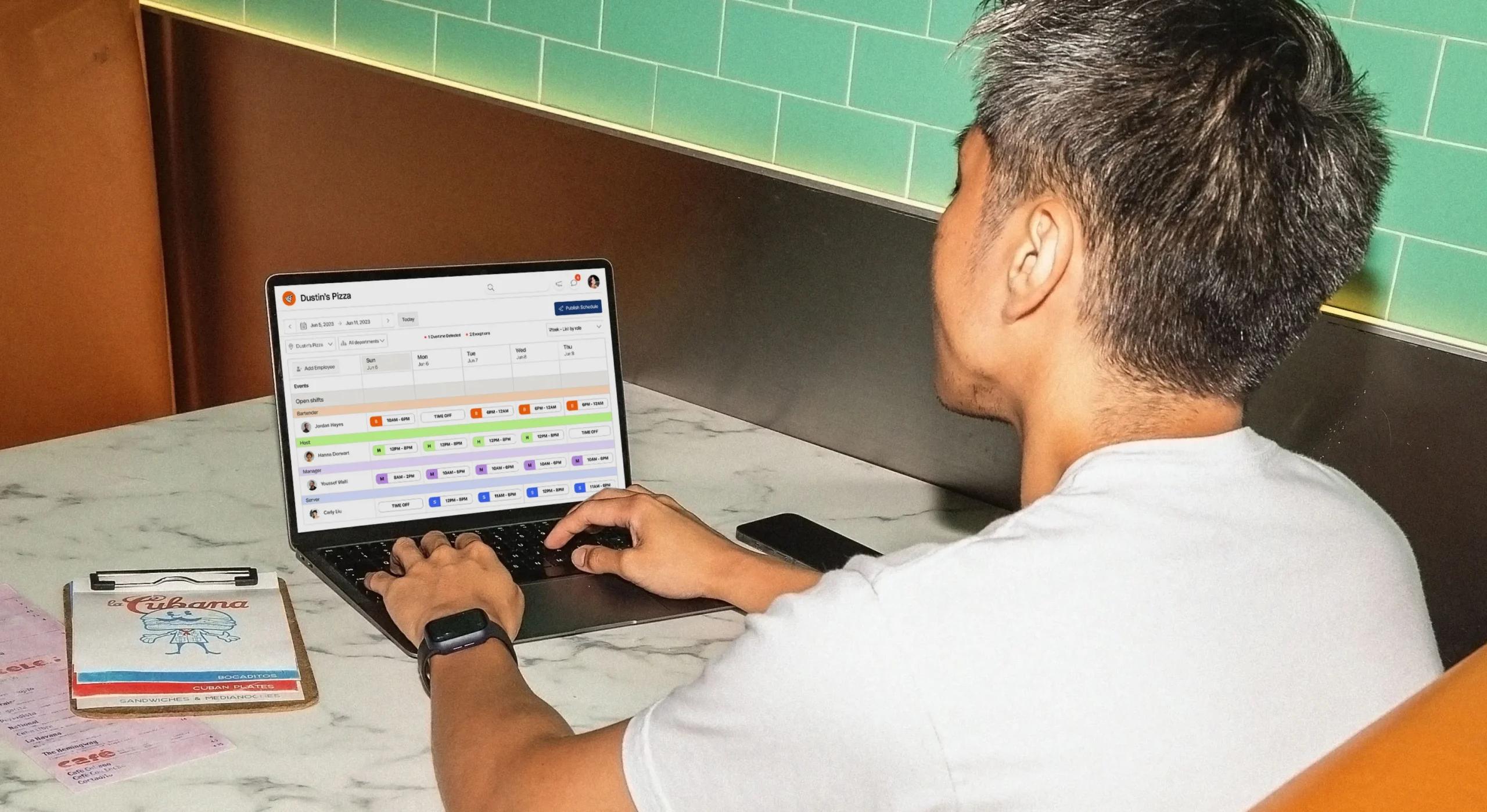 image of man using a laptop while on 7shifts scheduling software