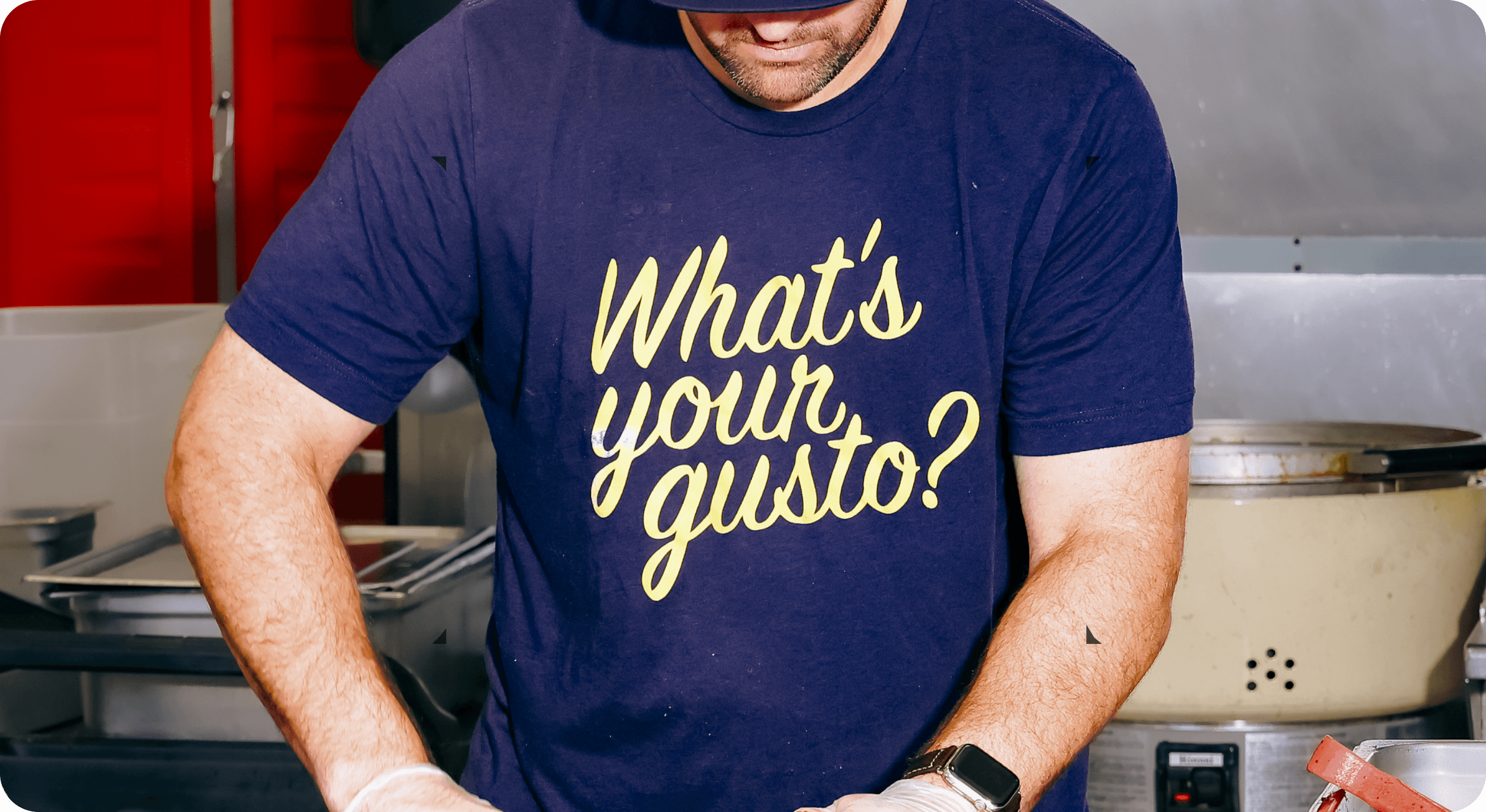 Man wearing staff tshirt at gusto! restaurant and cutting food in back of kitchen