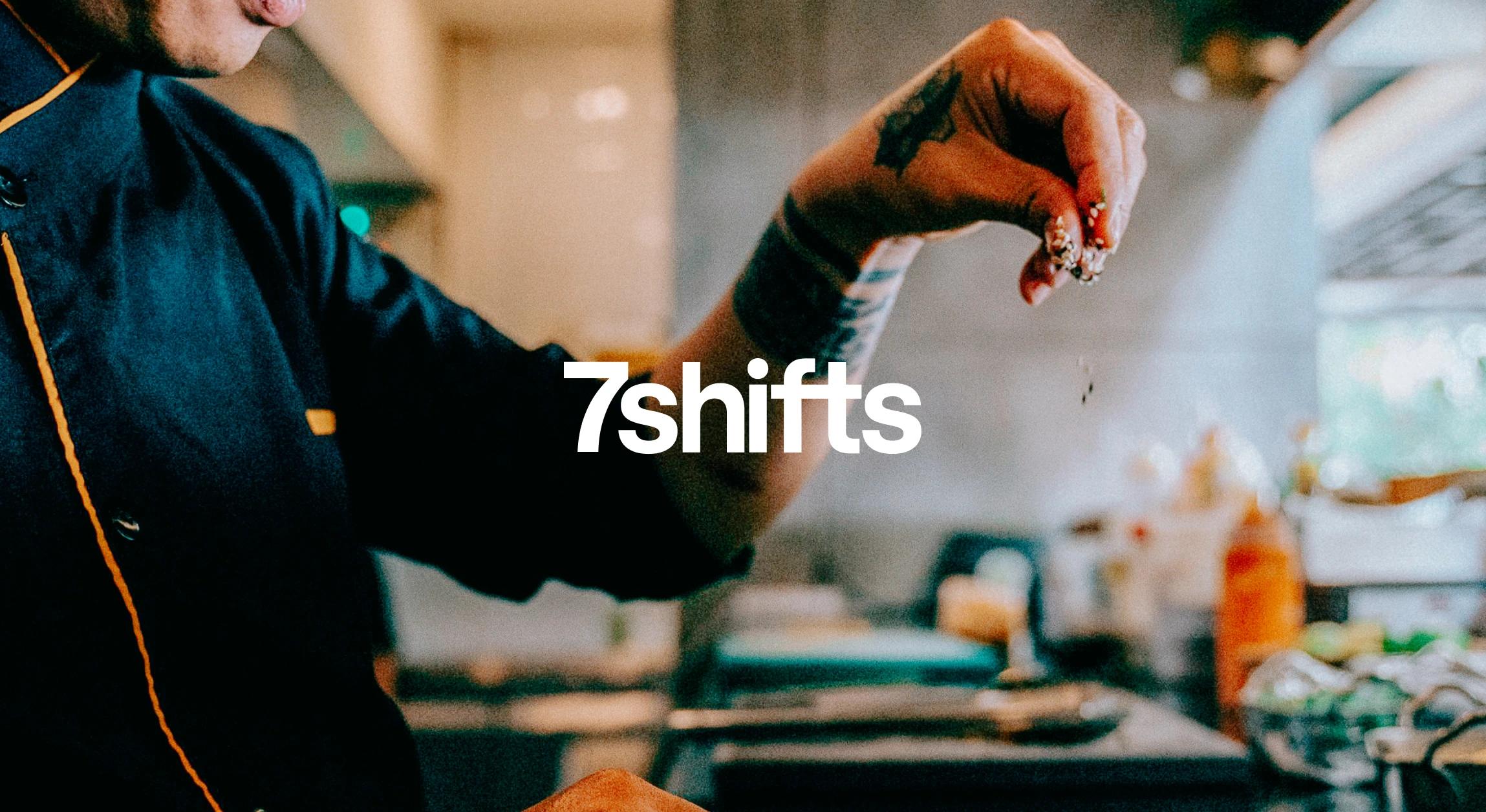 A chef's hand sprinkling seasoning on food in the kitchen.