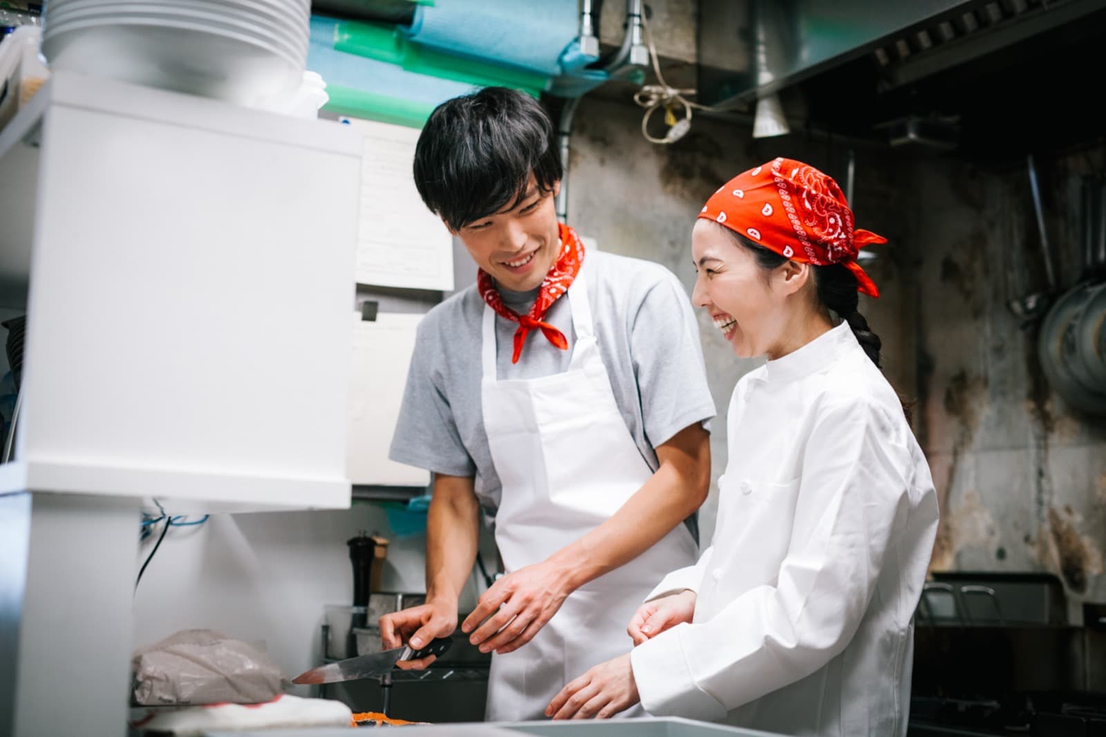 Two restaurant workers laughing while looking at a screen