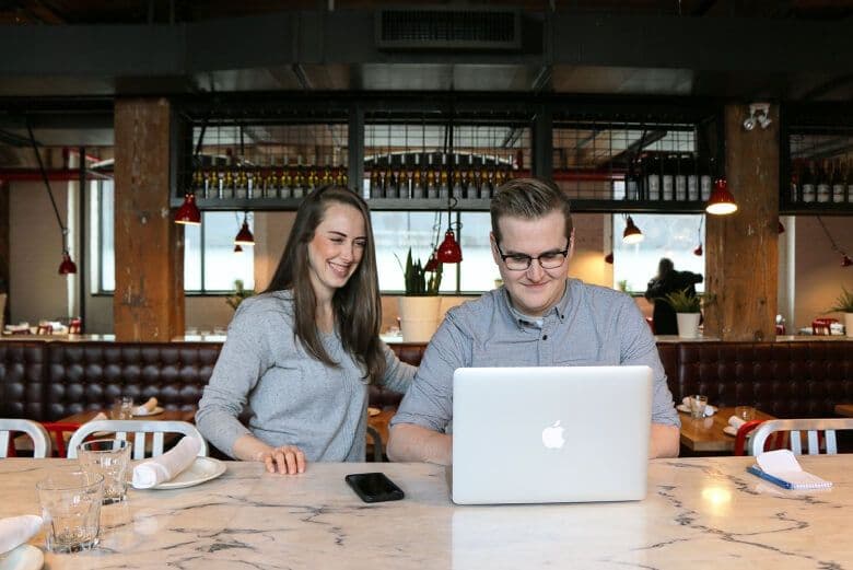 Two people working on a laptop in a café.