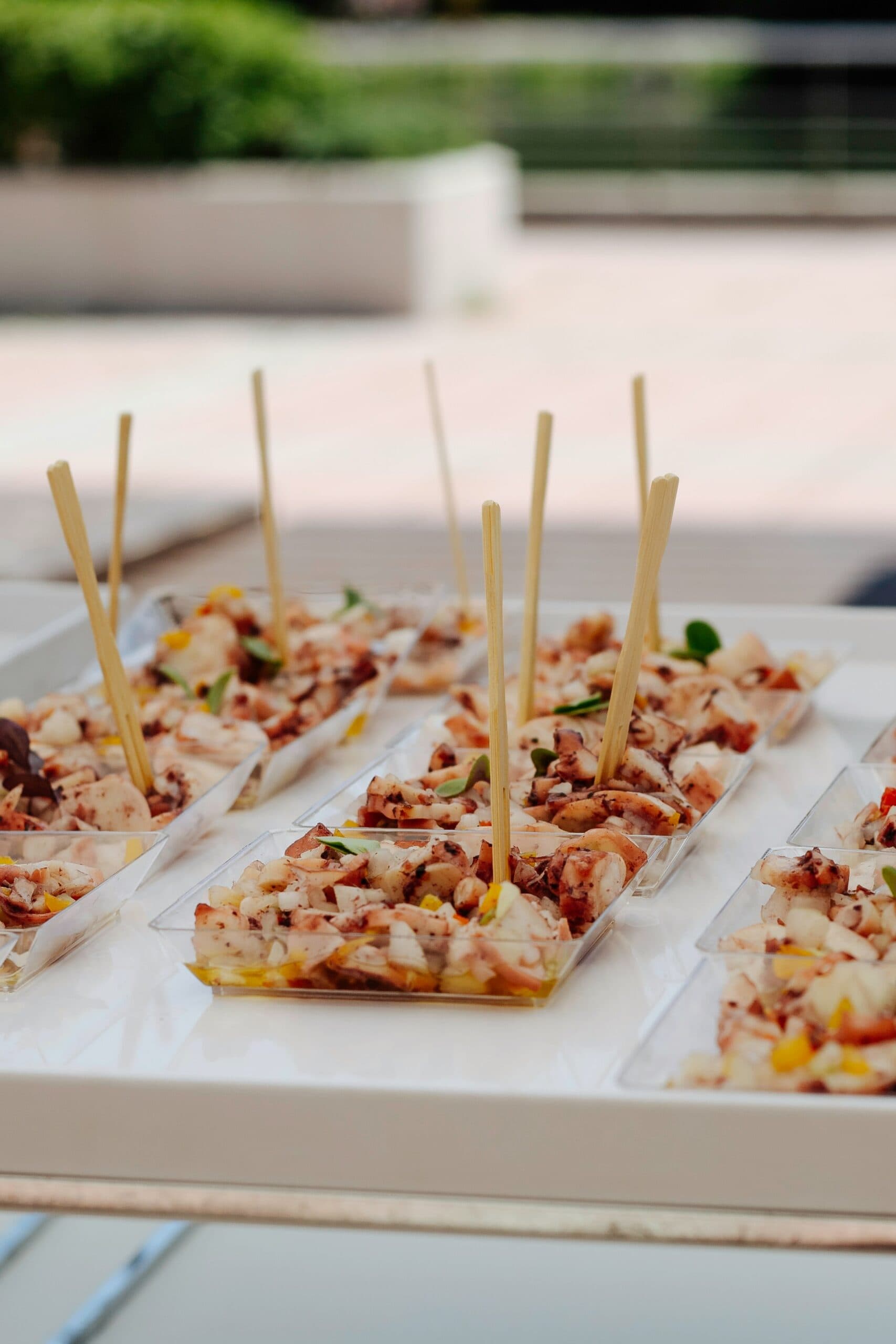 Seafood appetizers in clear trays with skewers.