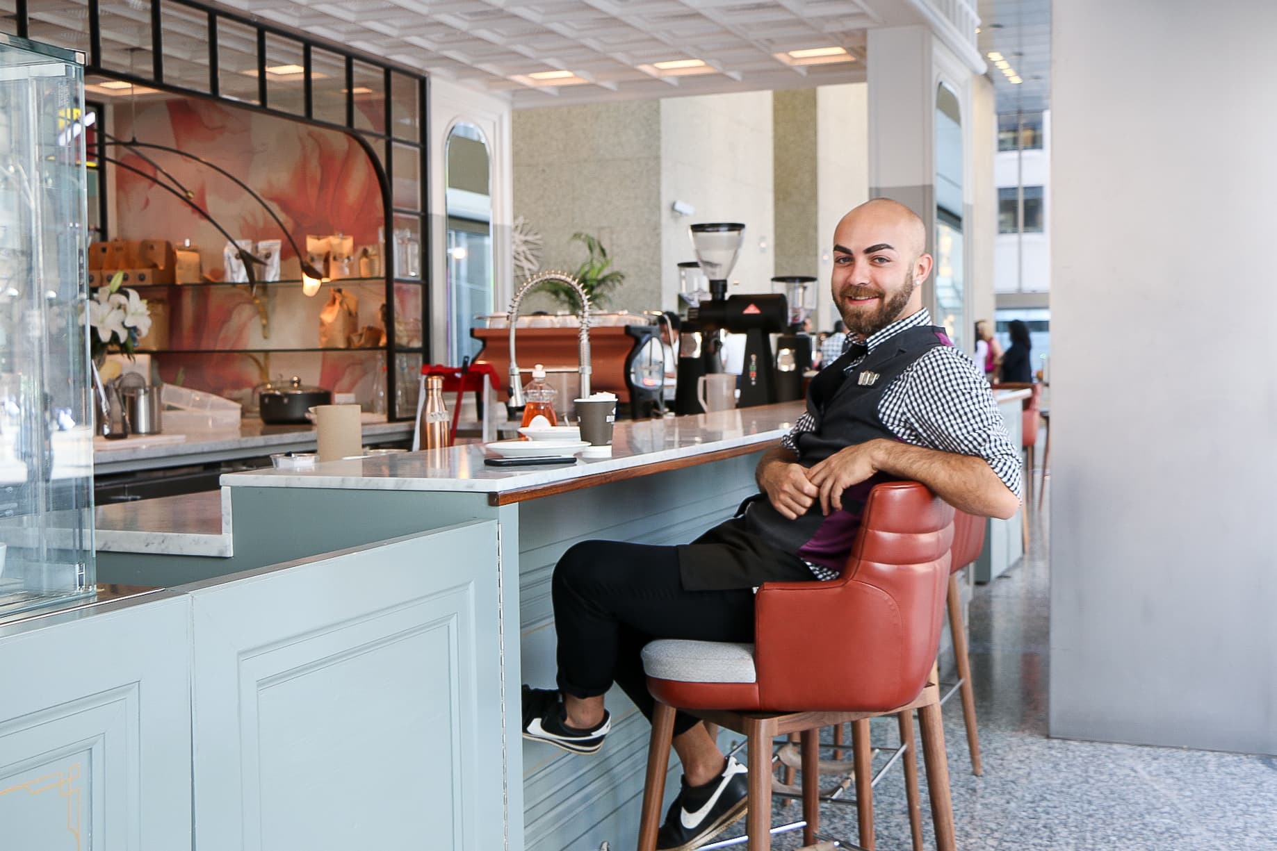 Smiling barista seated at a modern coffee bar