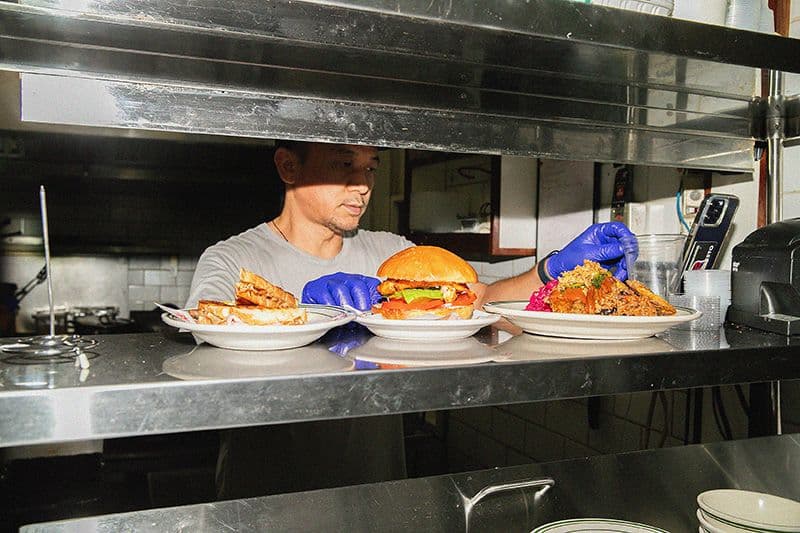 Chef preparing plates with various dishes in kitchen.