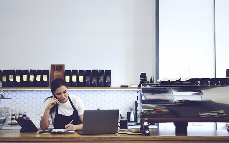 Barista working at coffee shop with laptop