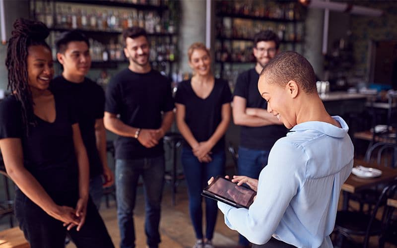 Manager training restaurant staff with tablet device.