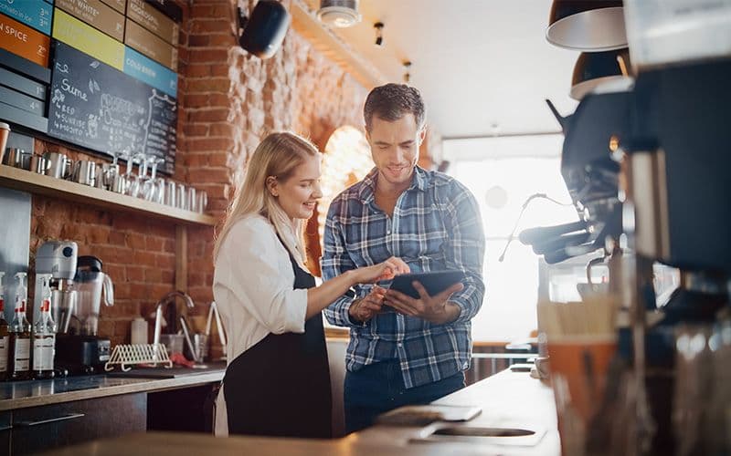Two cafe staff looking at tablet together.