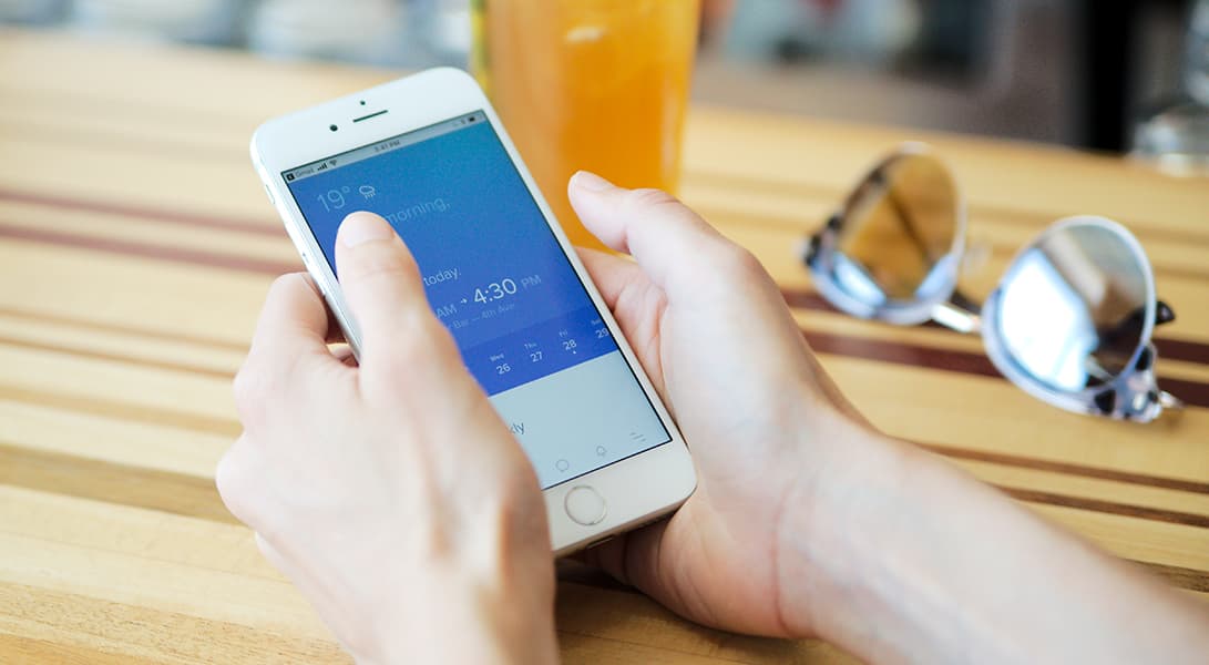 Person checking weather on smartphone screen.