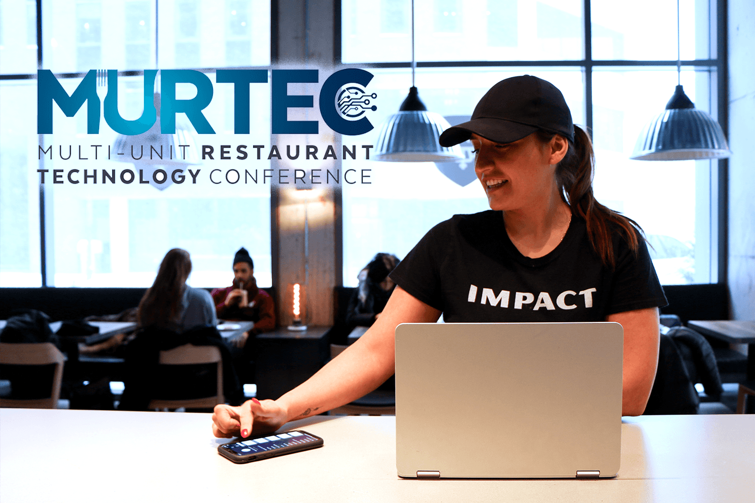 Woman at laptop in restaurant technology conference.