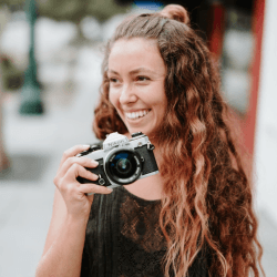 Smiling woman holding camera outdoors