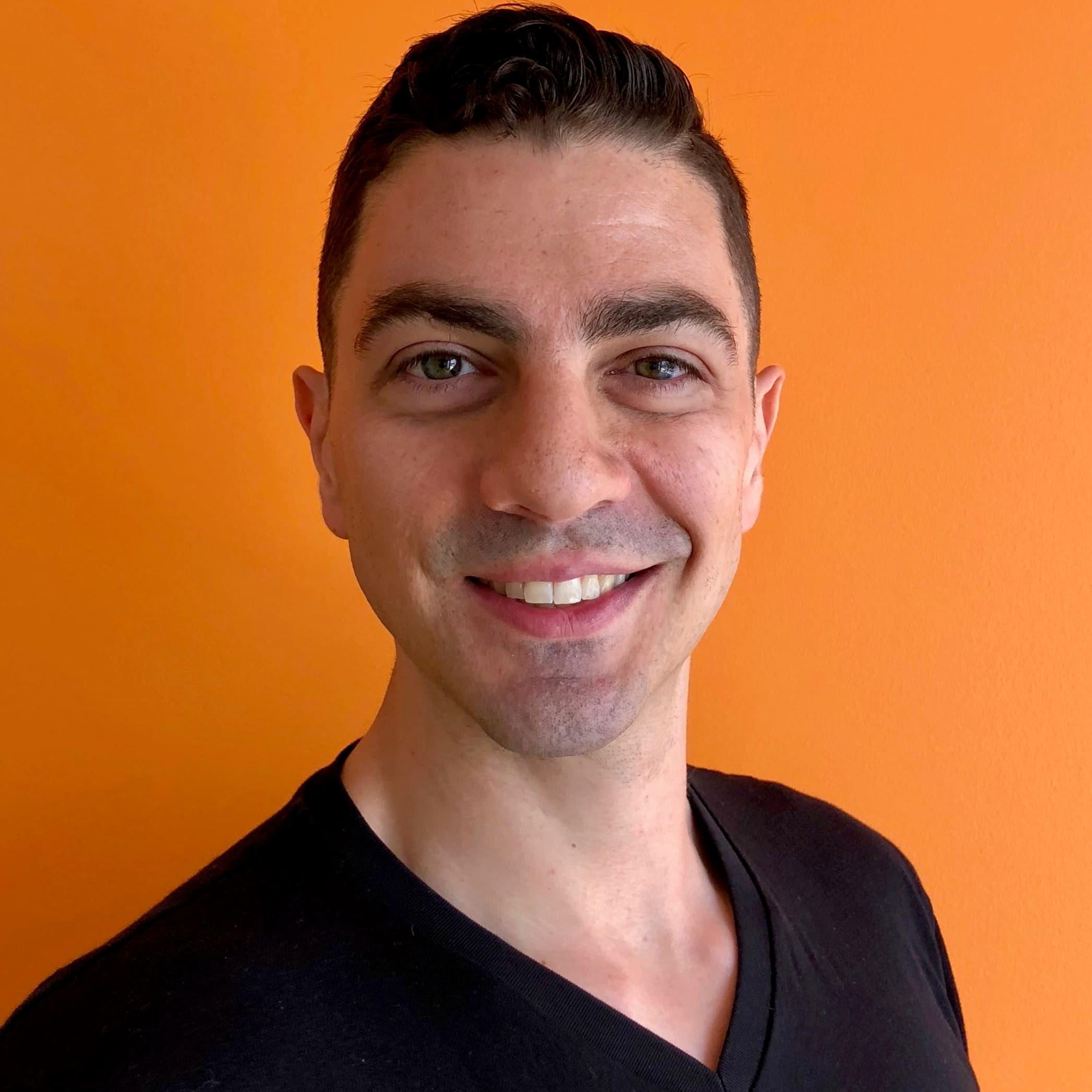 Smiling person in front of orange background