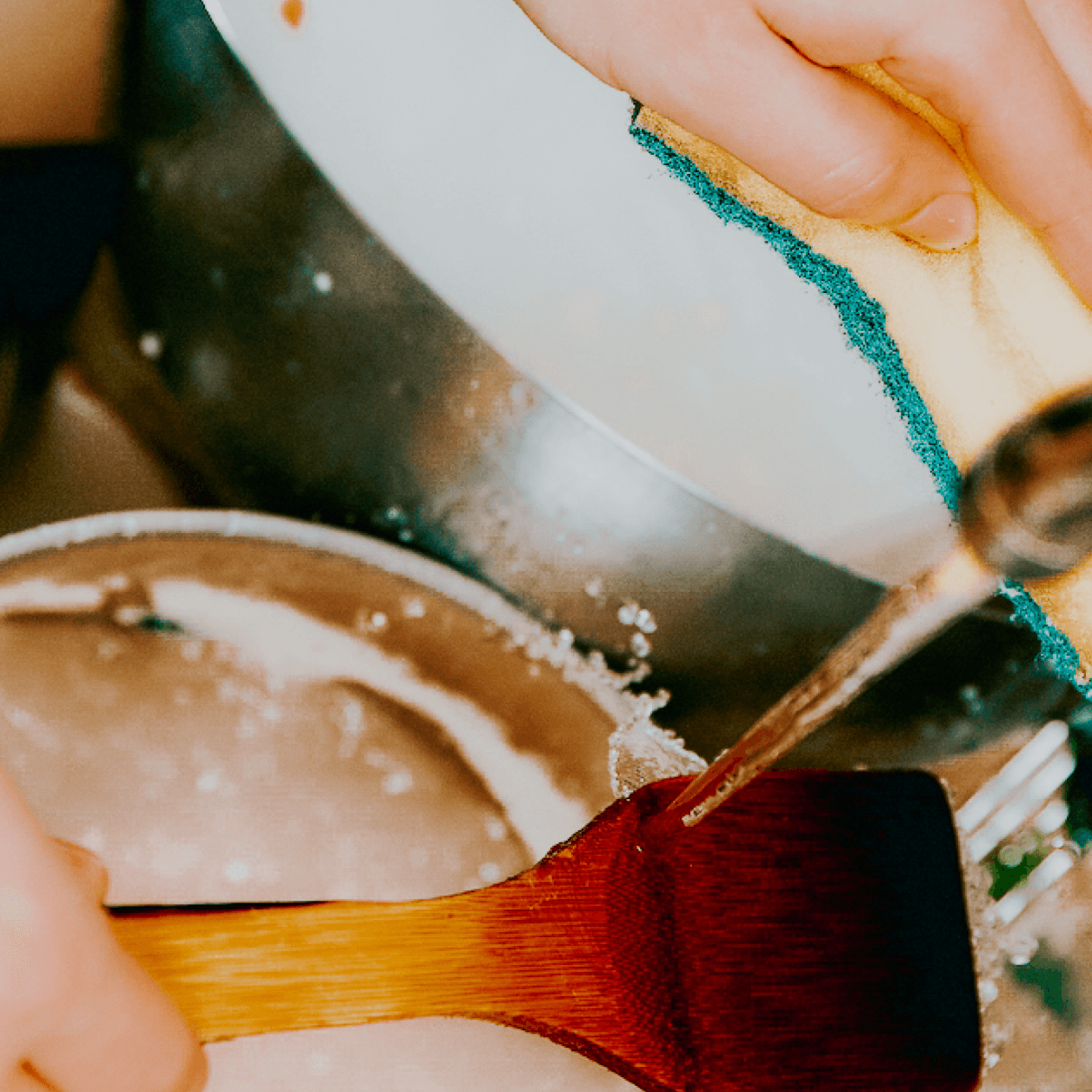 Person washing spatula in sink