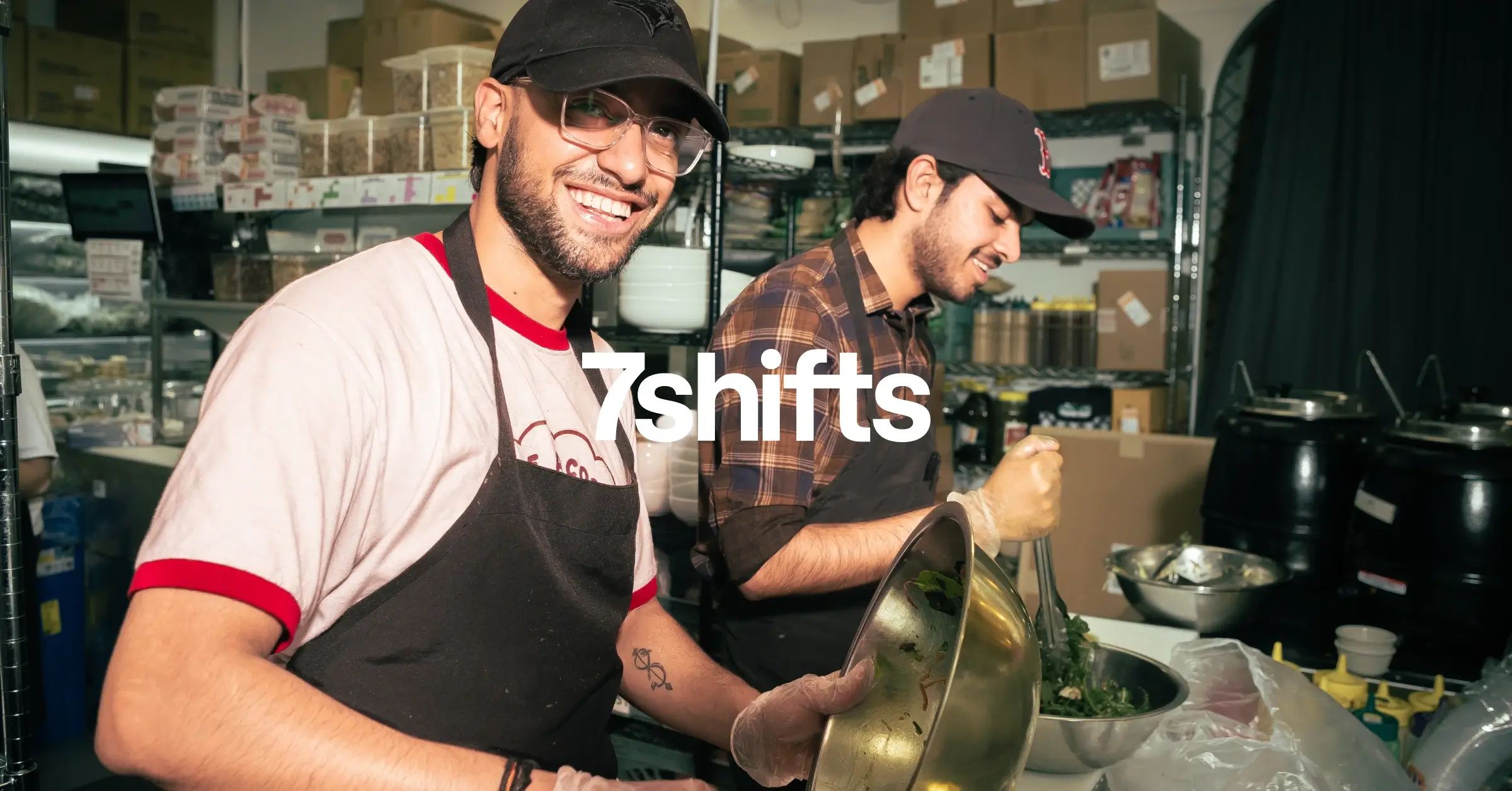 Two chefs working in a kitchen, smiling.