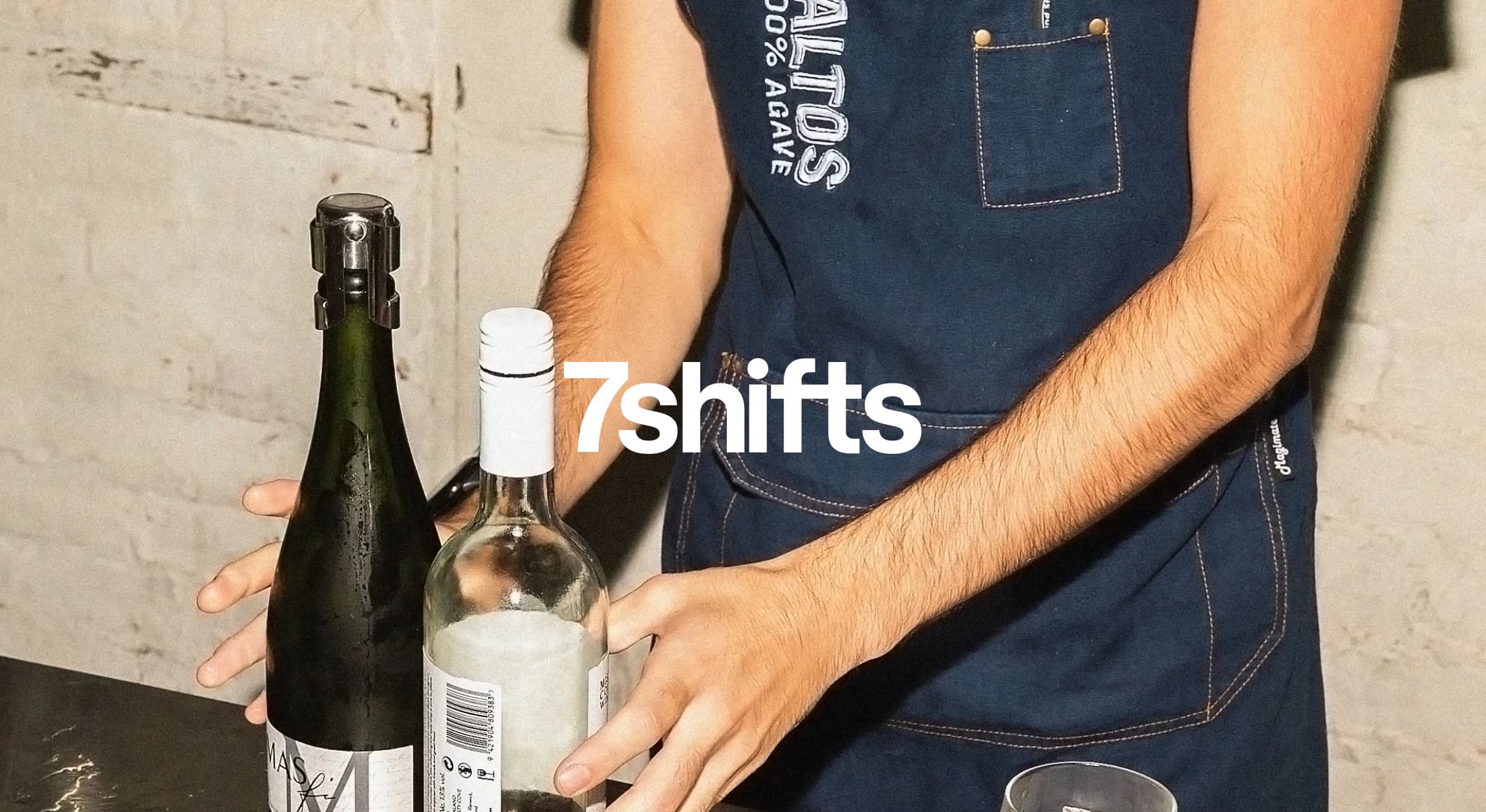 Person placing two bottles of wine on a table.