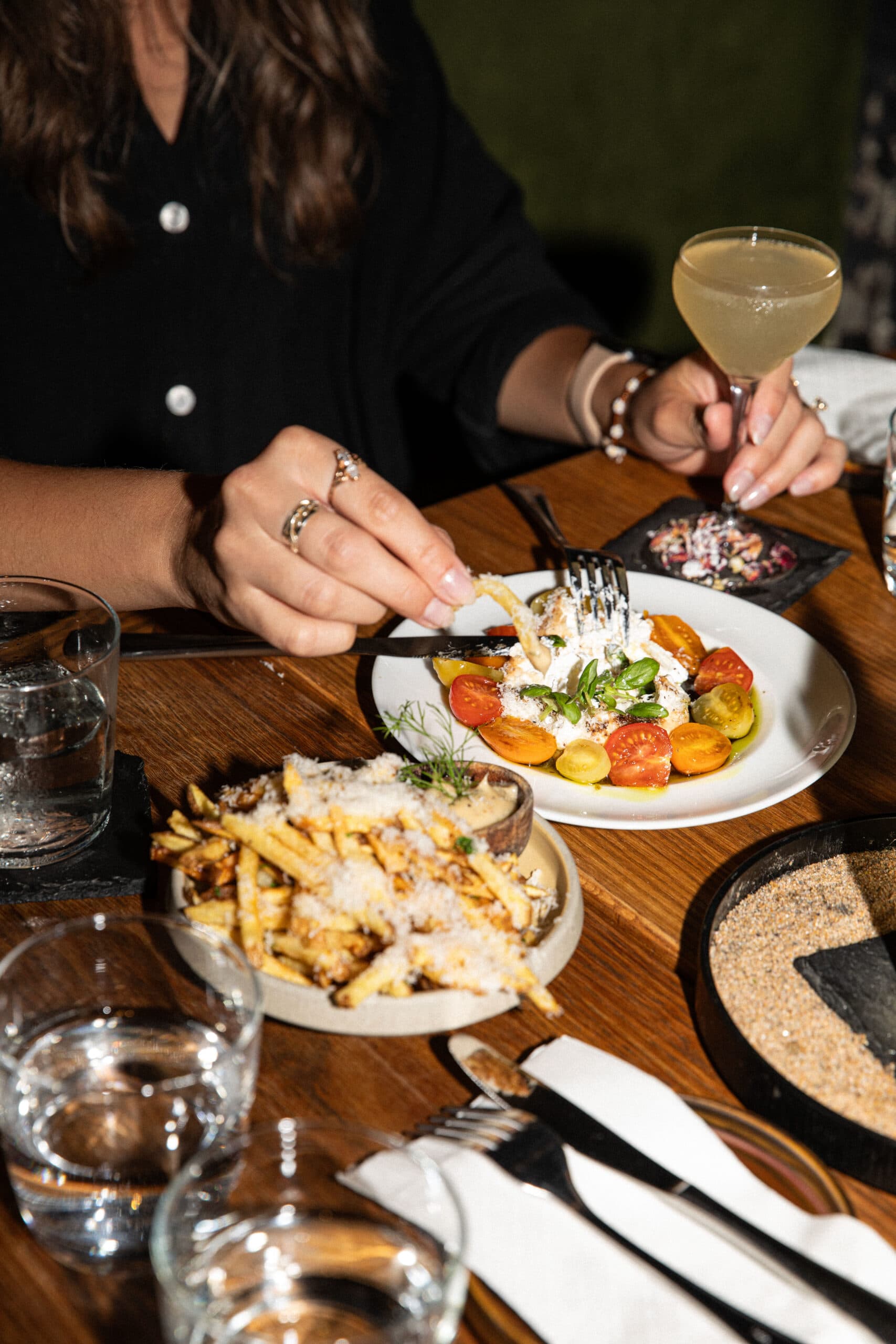 Dining table with salad, fries, and cocktail.